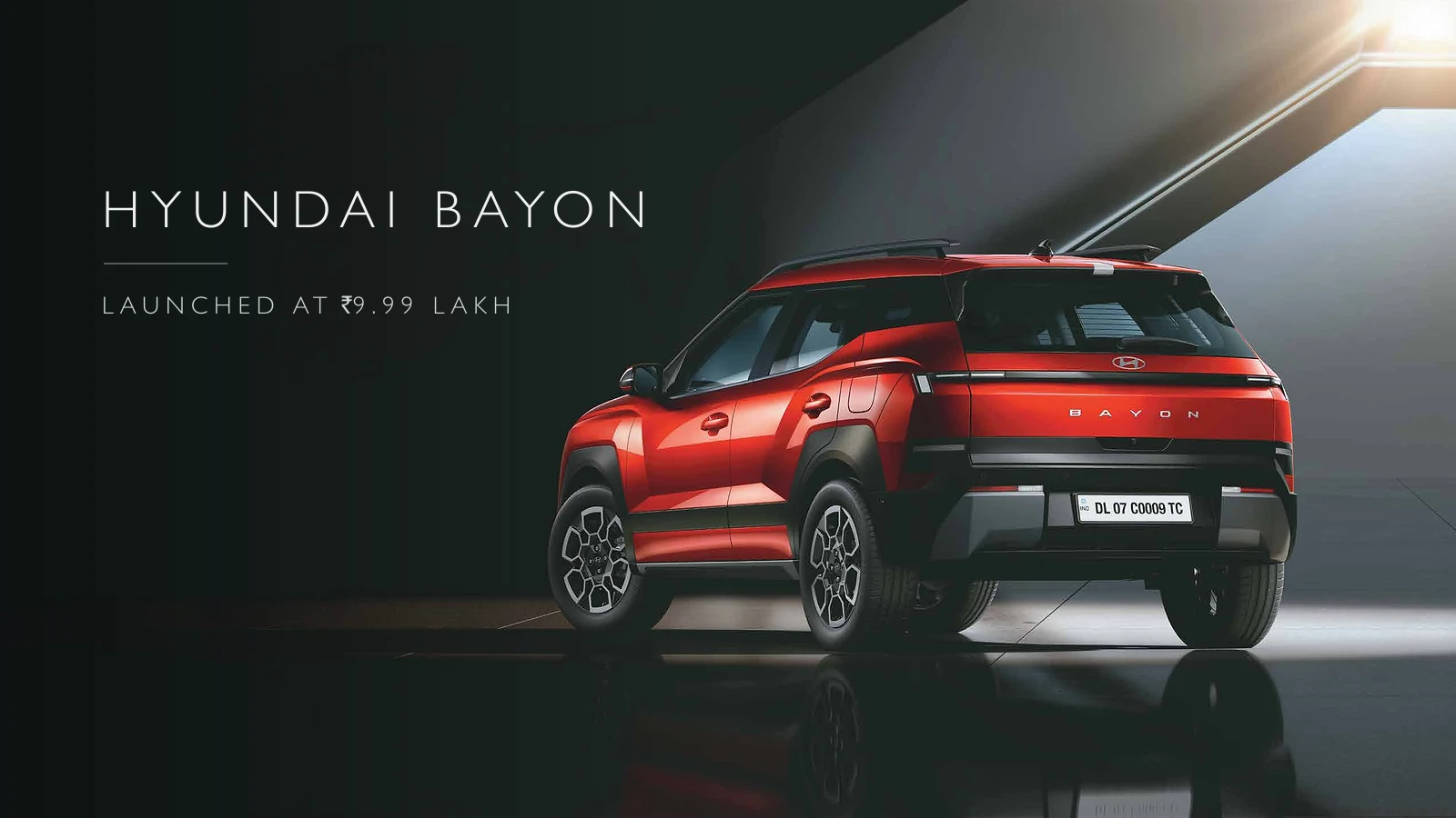 Rear three-quarter view of a red Hyundai Bayon in a dark studio, with Bayon lettering across the tailgate